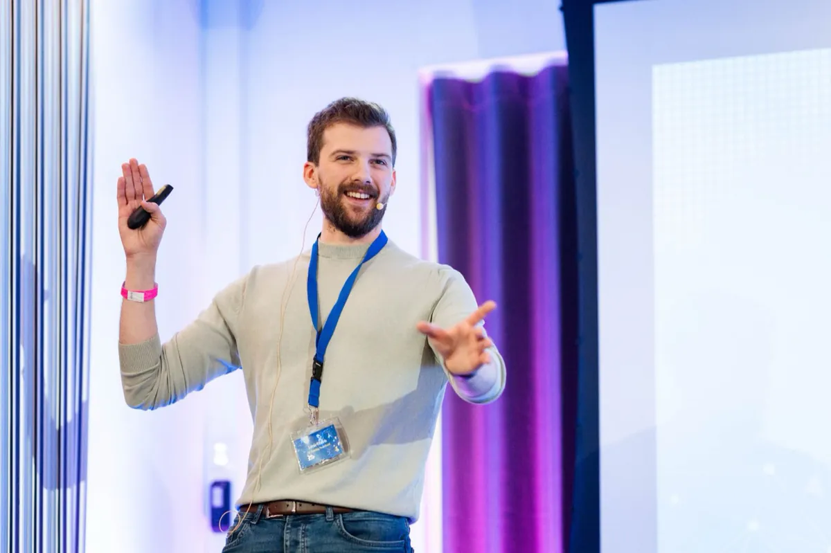 Jamie speaking on stage, gesturing to the audience